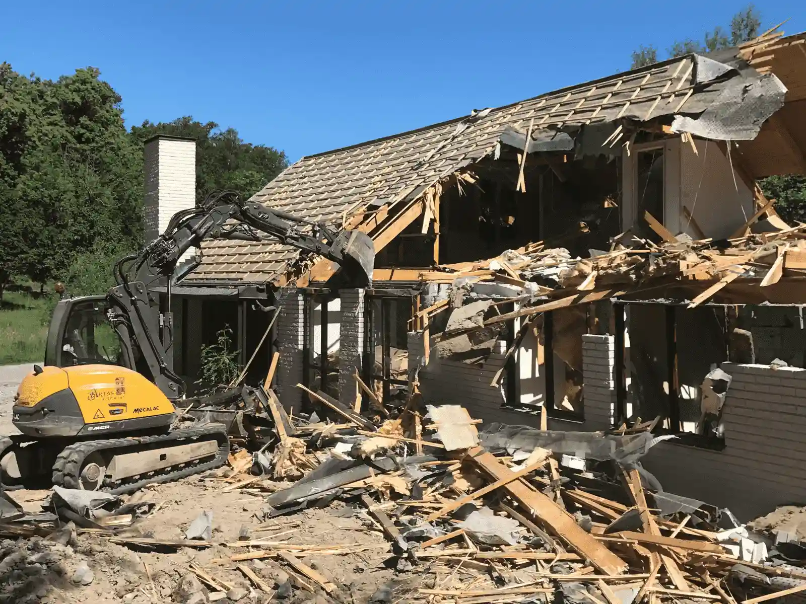en grävmaskin river ett tak i Stockholm vid rivningen av ett hus