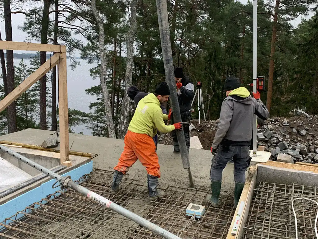 3 män gjuter betong i Danderyd nära poolen i en lyxvilla för en infinitypool i Stockholm
